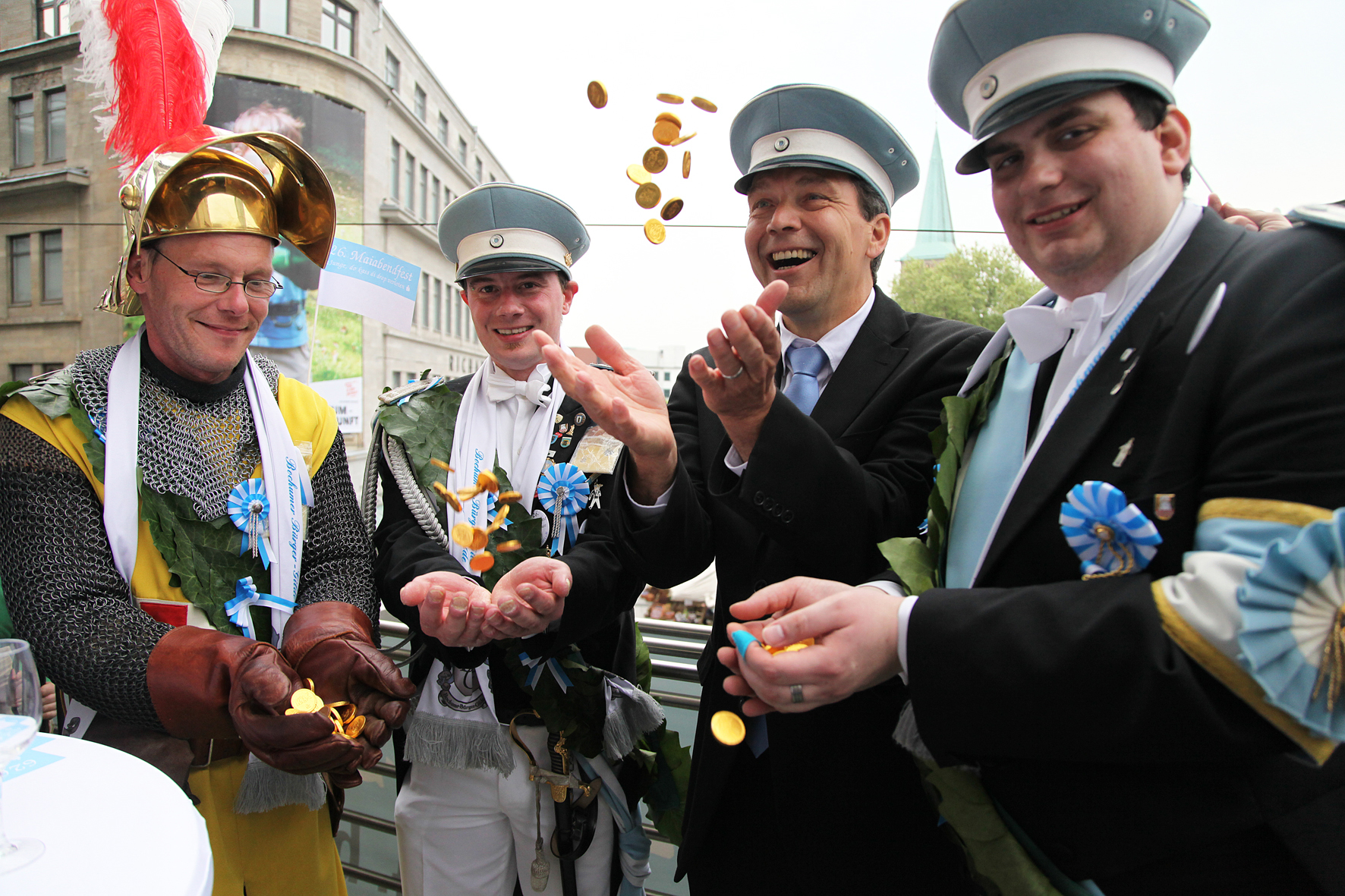 Vier Männer in Uniform, einer wirft Münzen in die Höhe.