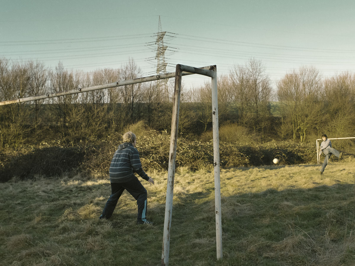 Zwei Jungen spielen Fußball auf einem Bolzplatz.