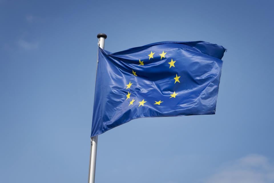 Flagge der EU in blau mit gelben Sternen in einem Kreis.