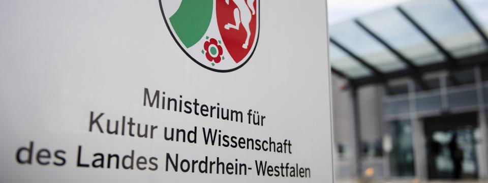 Schild vor dem Eingang des Ministeriums mit NRW-Landeswappen und der Aufschrift "Ministerium für Kultur und Wissenschaft des Landes Nordrhein-Westfalen"