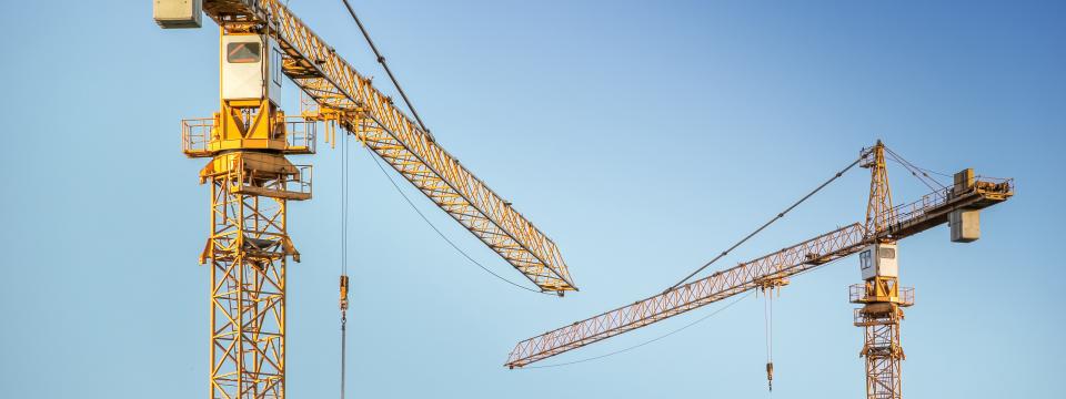 Zwei Baukräne vor blauem Himmel