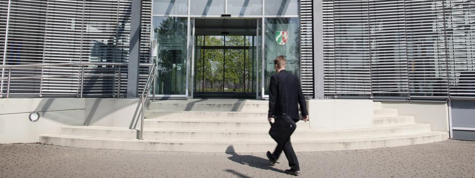 Ein Mann läuft mit Aktentasche in der Hand auf fas Gebäude des Ministeriums zu.