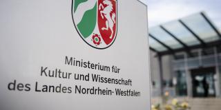 Schild vor dem Eingang des Ministeriums mit NRW-Landeswappen und der Aufschrift "Ministerium für Kultur und Wissenschaft des Landes Nordrhein-Westfalen"